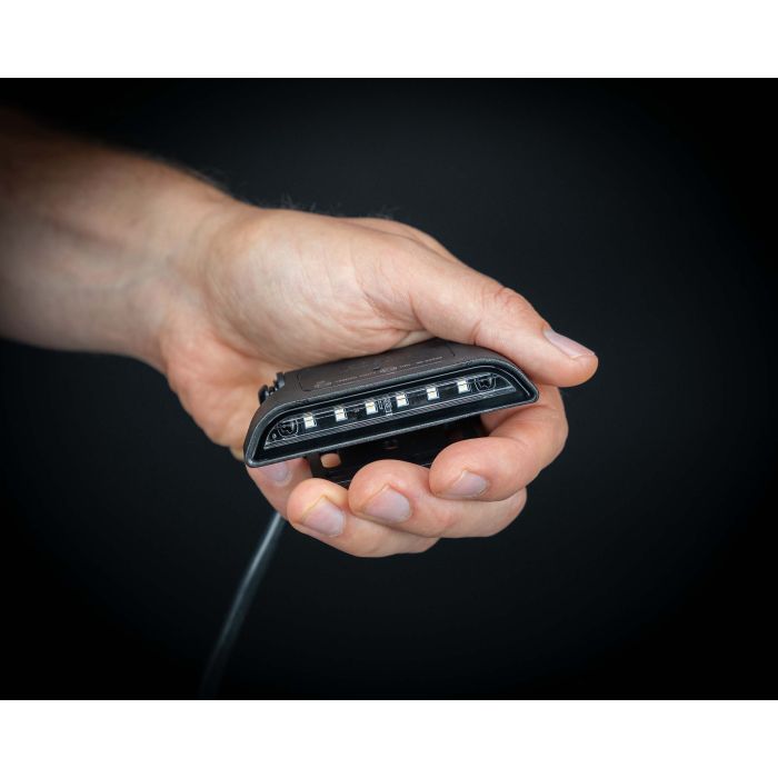 LEDSON Nano baklygte, holdes i en hånd, sort baggrund