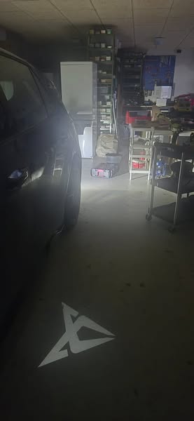 Bil med Cupra logo lysprojektion på jorden fra døren